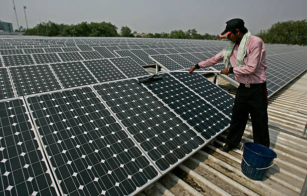 Indian worker cleaning large-scale solar panel array